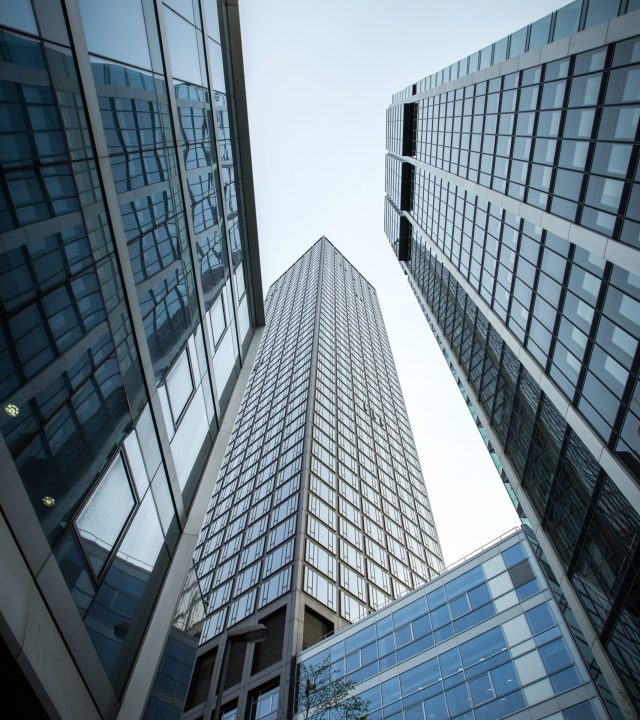 A vertical low angle shot of high rise skyscrapers in a glass facade in Frankfurt, Germany